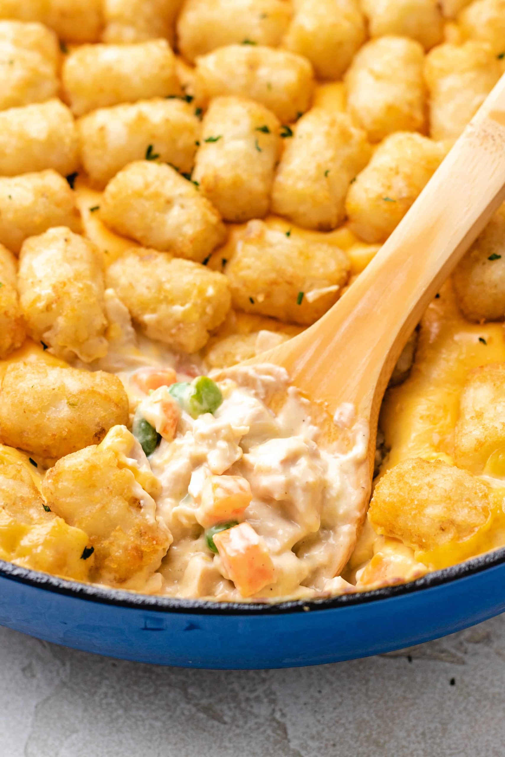 Wooden spoon scooping creamy filling out of a casserole.