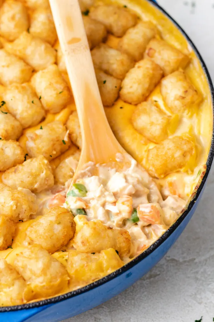 Close up view of a blue dish filled with chicken and tots.