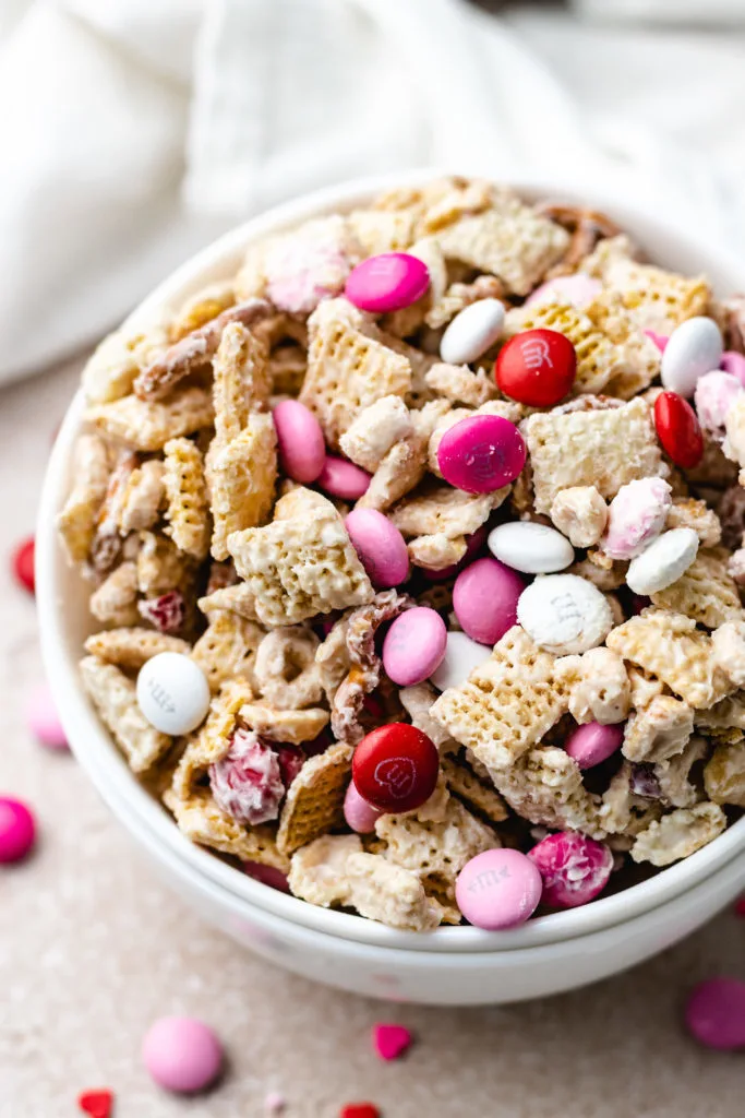 Angled view of valentine's chex mix in a white bowl.