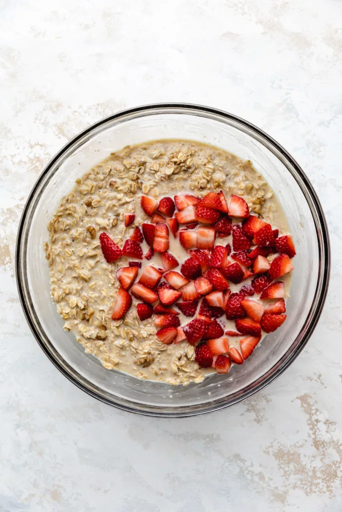 Strawberries on top of a bowl of unbaked oatmeal filling.