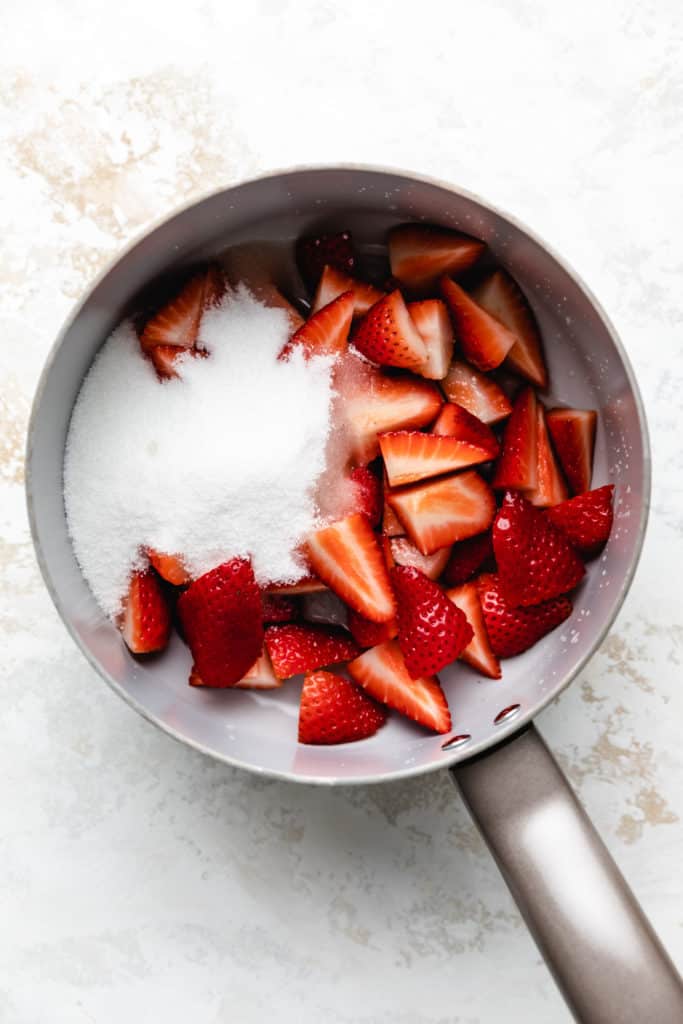 Strawberries and sugar in a pan.