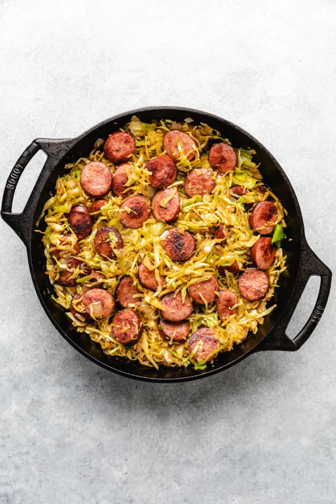 Cabbage and sausage in a pan.