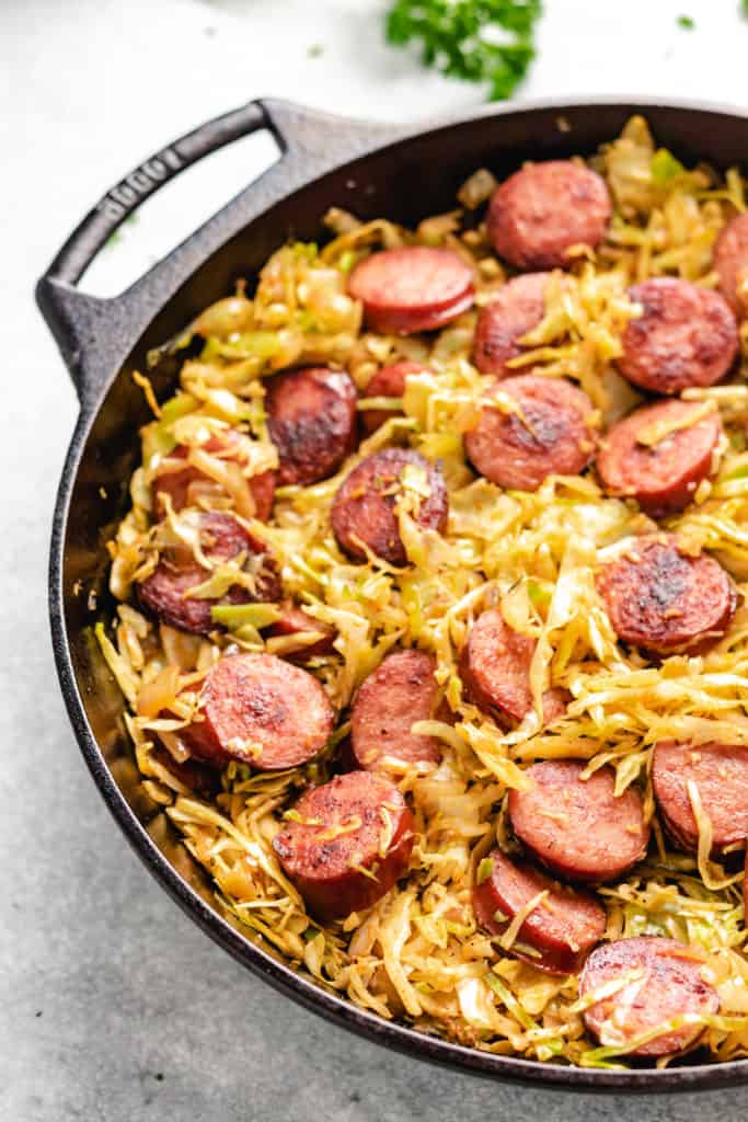 Close up view of sausage rounds mixed with seasoned cabbage.
