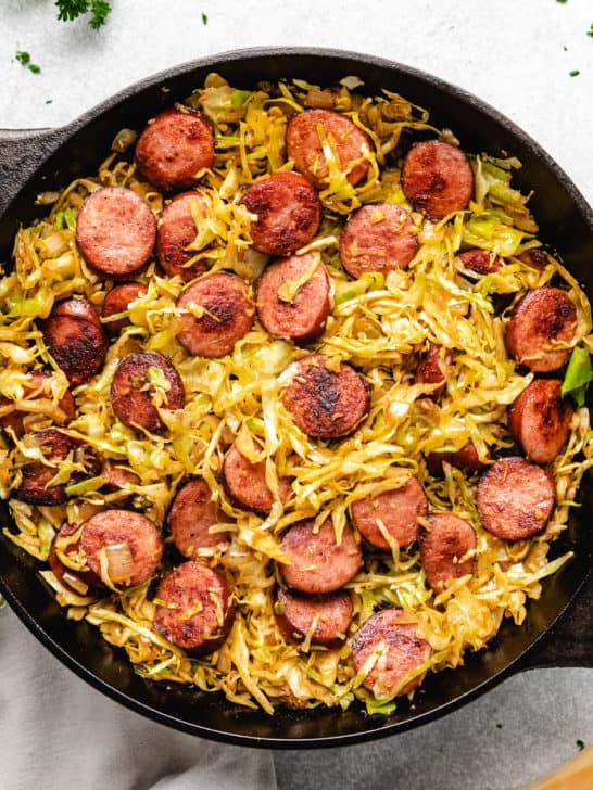 Top down view of sausage and fried cabbage in cast iron.