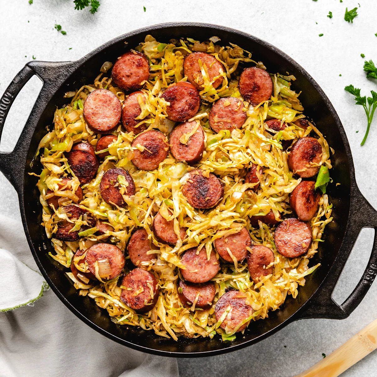 Top down view of sausage and fried cabbage in cast iron.