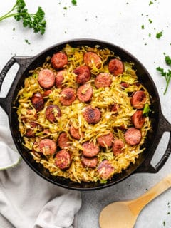 Round pan filled with fried cabbage with sausage.