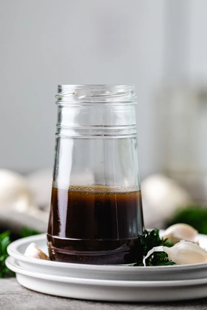 Jar of balsamic and maple dressing on a plate.