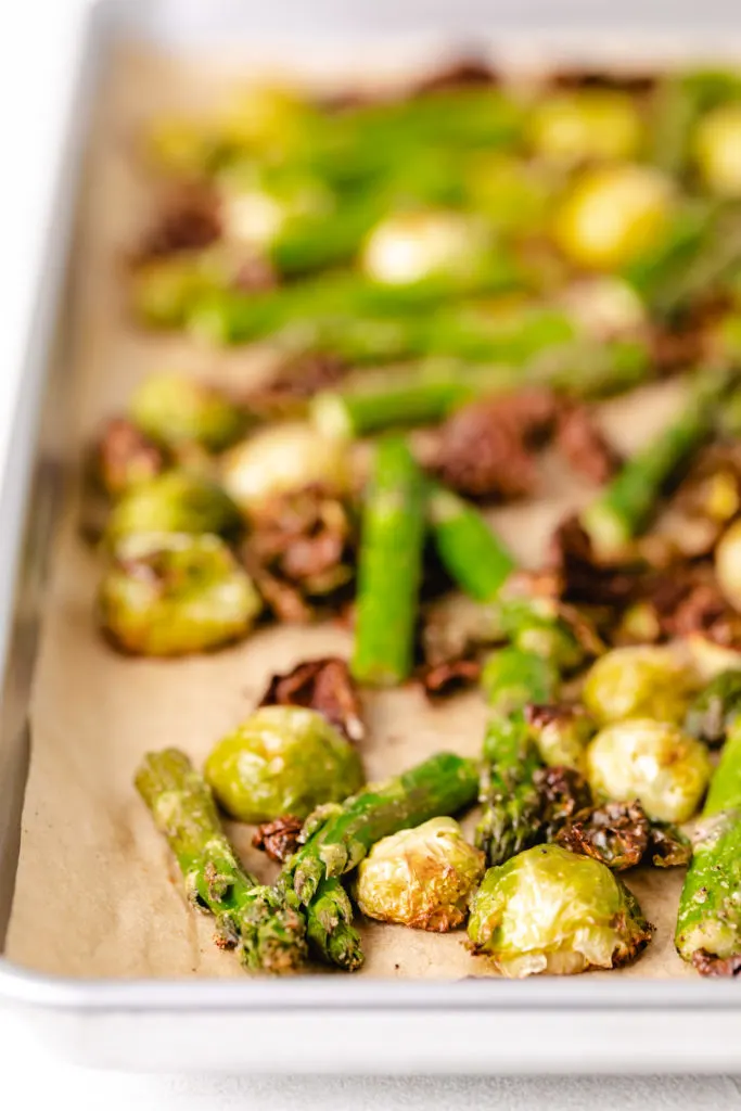 Sheet pan filled with roasted asparagus and brussels sprouts.