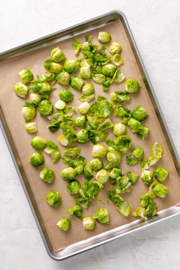 Unbaked brussels sprouts on a baking sheet.