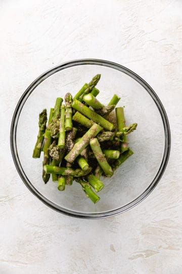 Seasonings and oil over asparagus.