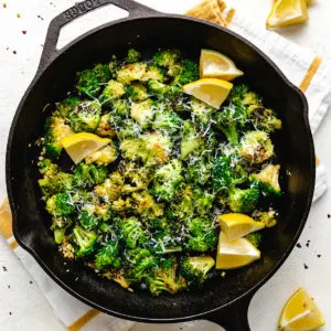 Top down view of a cast iron pan filled with sauteed broccoli.