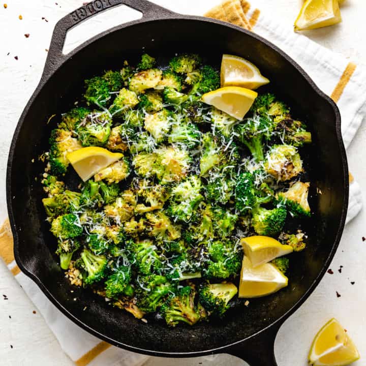 Top down view of a cast iron pan filled with sauteed broccoli.