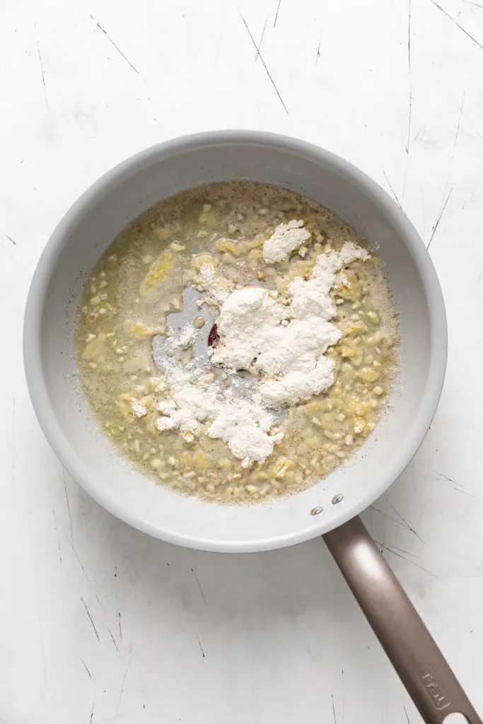 Flour sprinkled over melted butter in a pan.