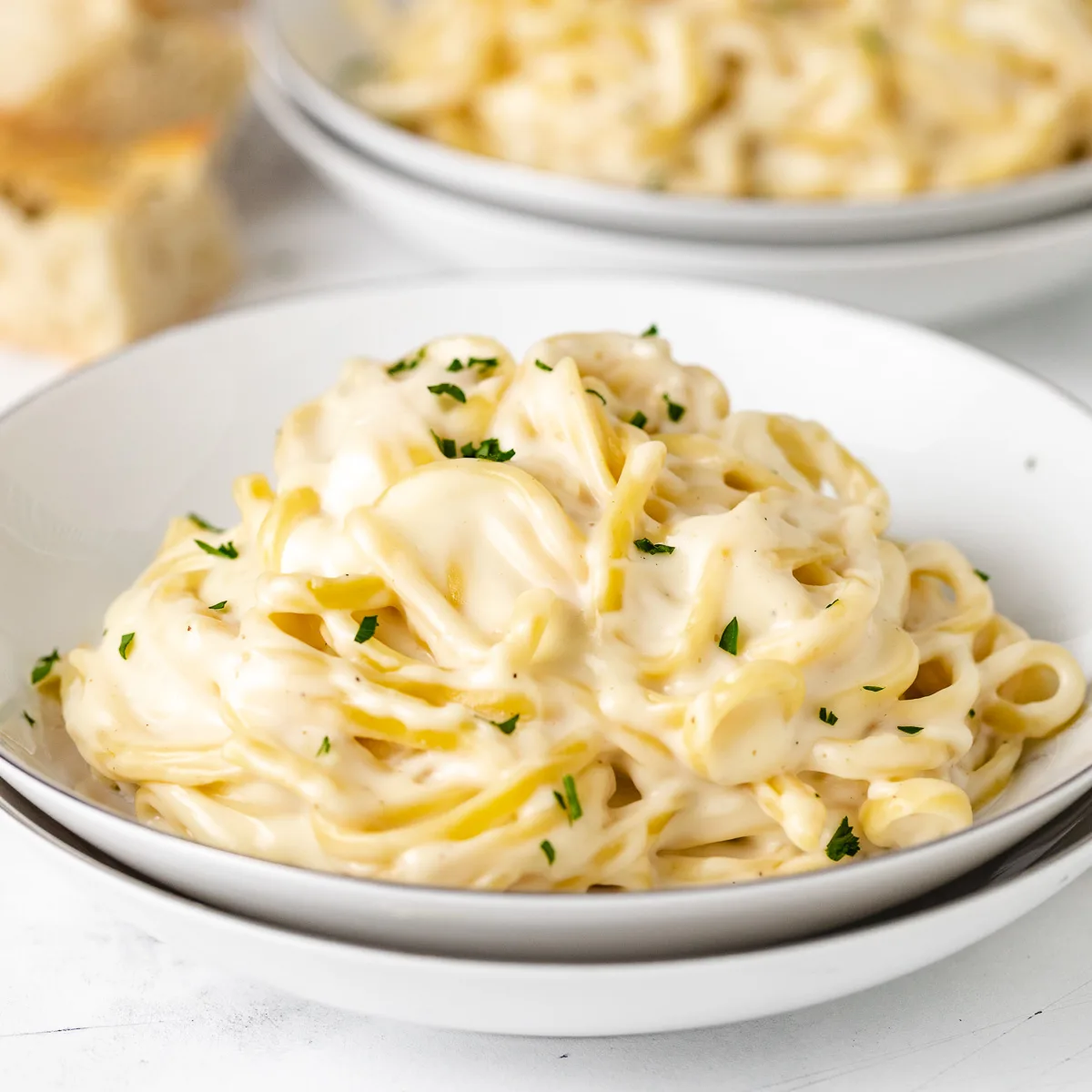 Close up view of garlic parmesan pasta in a stack of bowls.