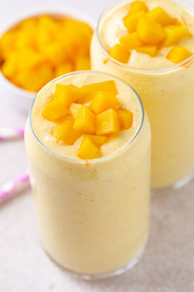 Two glasses filled with mango and banana smoothie.