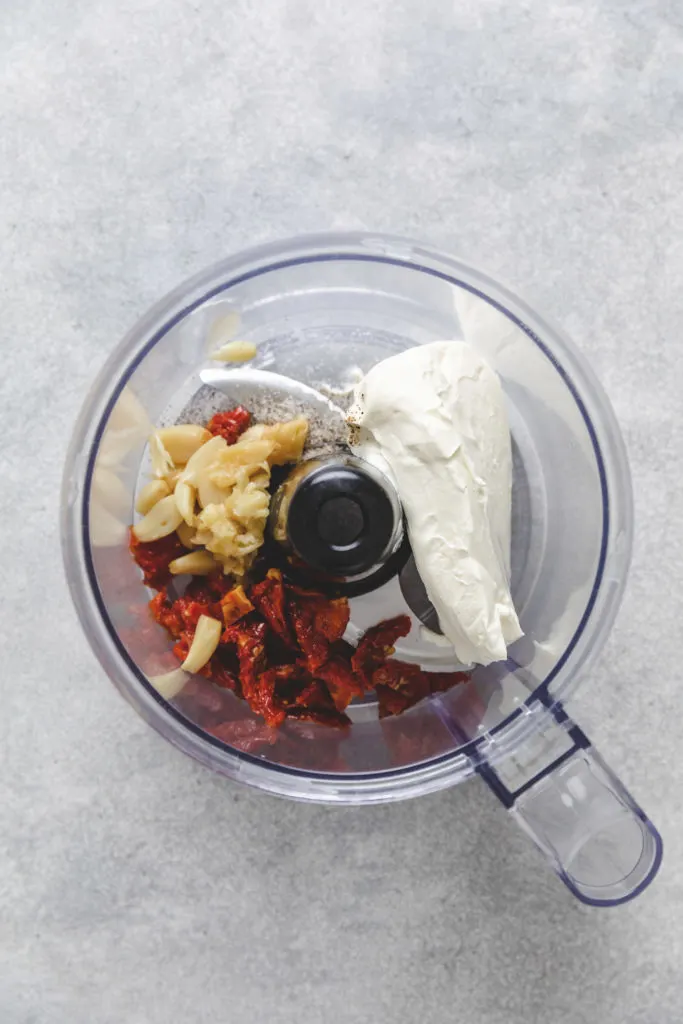 Cream cheese, garlic, and sun-dried tomatoes in a food processor.