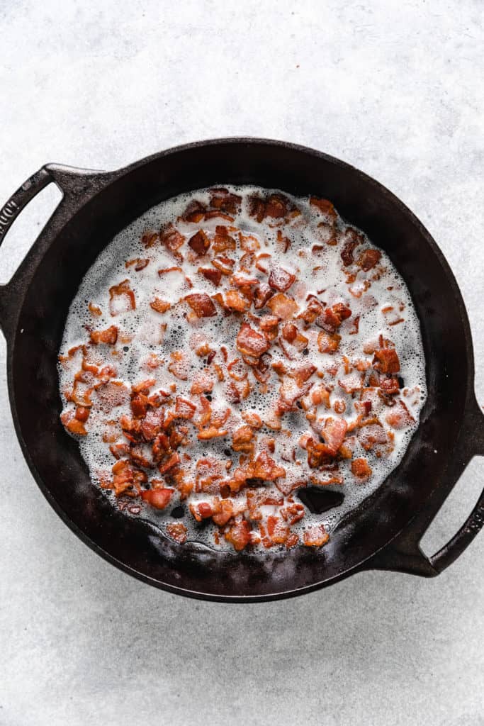 Bacon cooking in a cast iron pan.