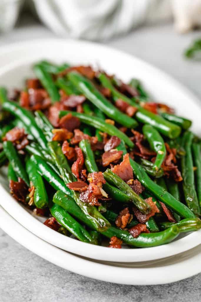 Side view of green beans with bacon on a serving platter.