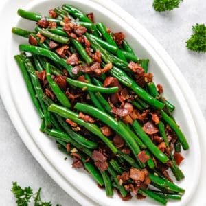 Top down view of sauteed green beans with garlic and bacon.