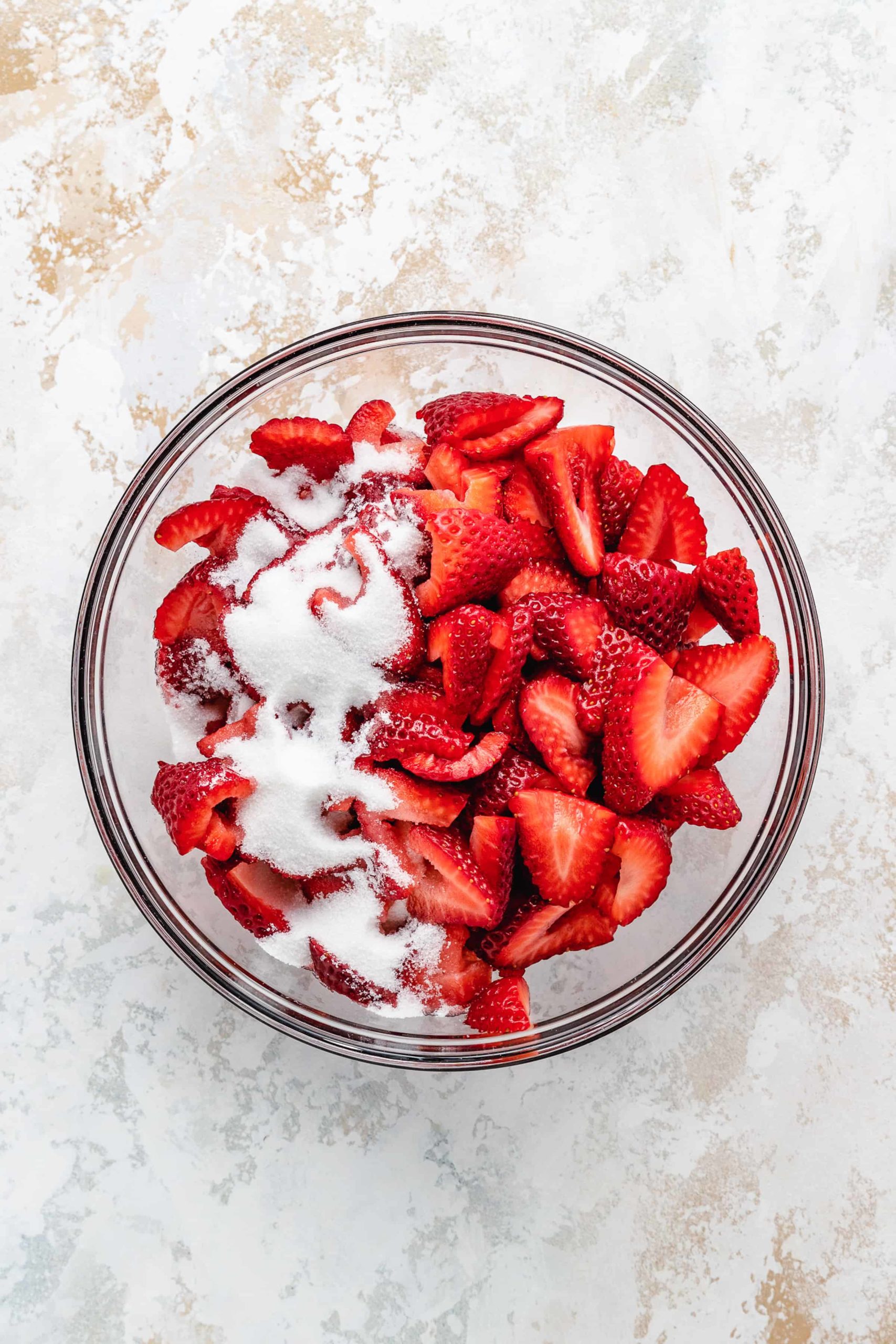 Strawberries and sugar in a bowl.