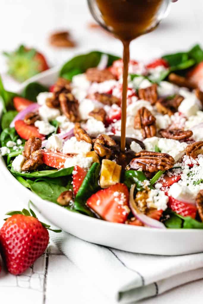 Balsamic vinegar being poured over a salad.