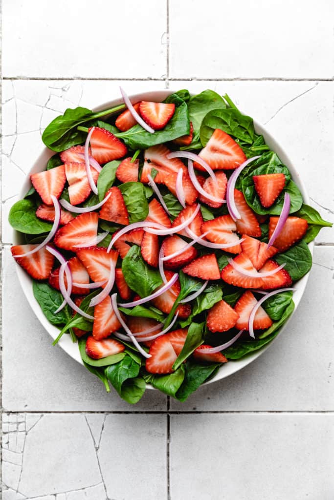 Onions and strawberries on top of spinach.