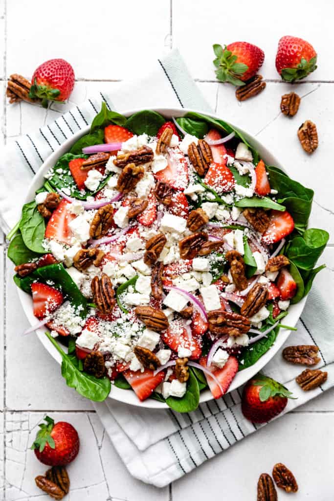 Spinach salad with fruit in a bowl.