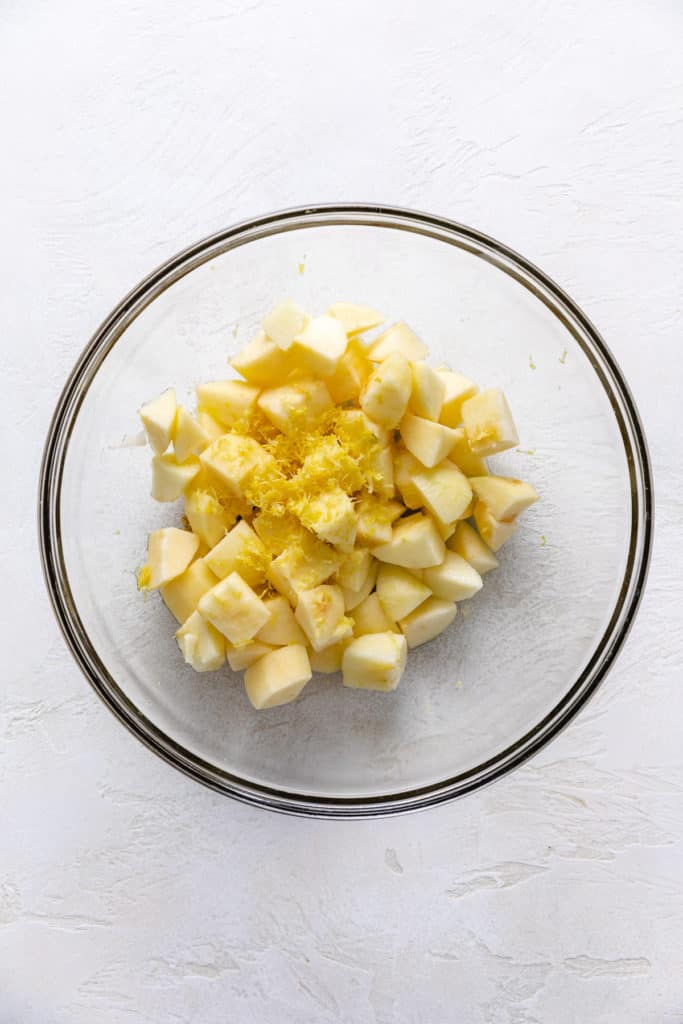 Apples, lemon juice and lemon zest in a bowl.