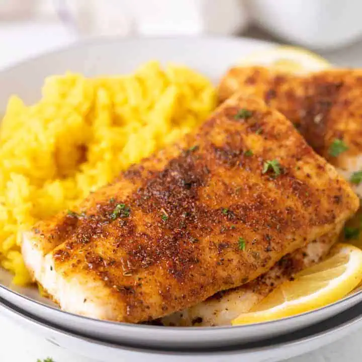 Close up view of a baked mahi mahi filets with lemon on a stack of bowls.