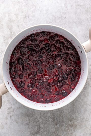 Large saucepan filled with whole blackberries and sweetened juice.