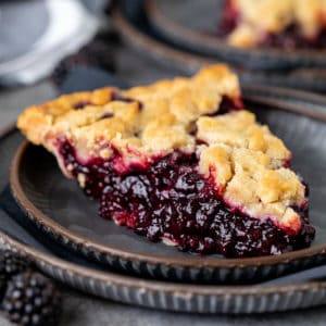 Side view of a slice of blackberry crumble pie.