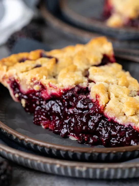Side view of a slice of blackberry crumble pie.