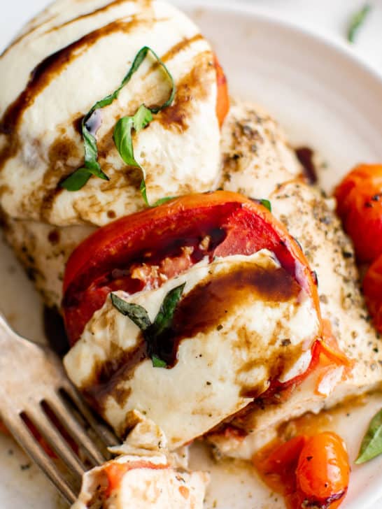 Close up view of a chicken breast with mozzarella, tomatoes, and basil.