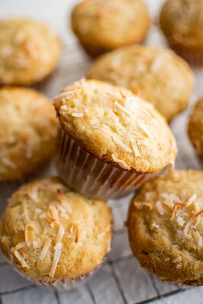 Close up view of toasted coconut muffins on a cooling rack.