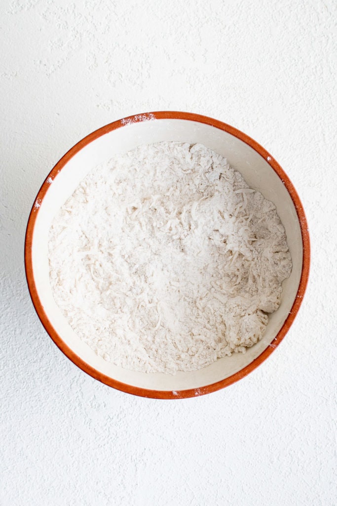 Flour, coconut, sugar, brown sugar, baking powder, baking soda and salt mixed in a bowl.