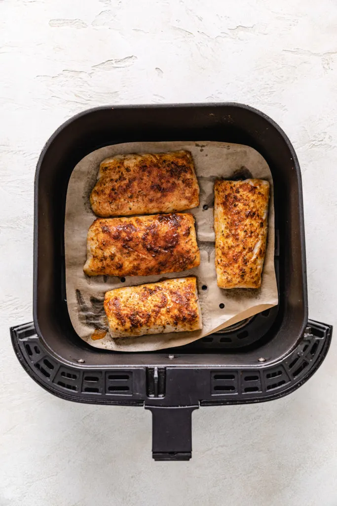 Cooked mahi mahi in an air fryer basket.