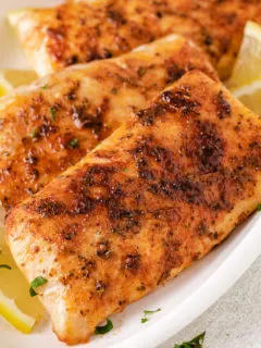 Close up view of fish on a large white plate.