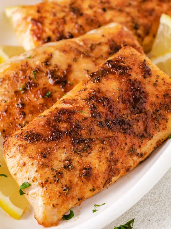 Close up view of fish on a large white plate.
