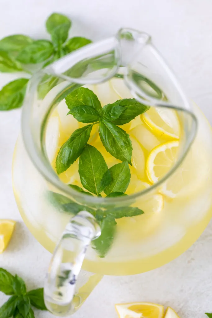 Fresh basil leaves in a pitcher of lemonade.