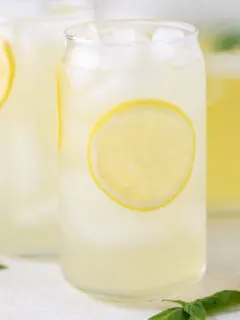 Close up view of a glass of lemonade next to a lemon wedge.
