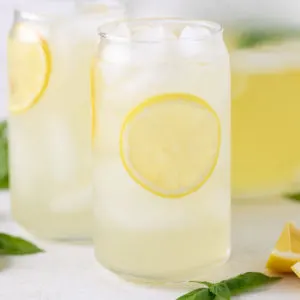 Close up view of a glass of lemonade next to a lemon wedge.