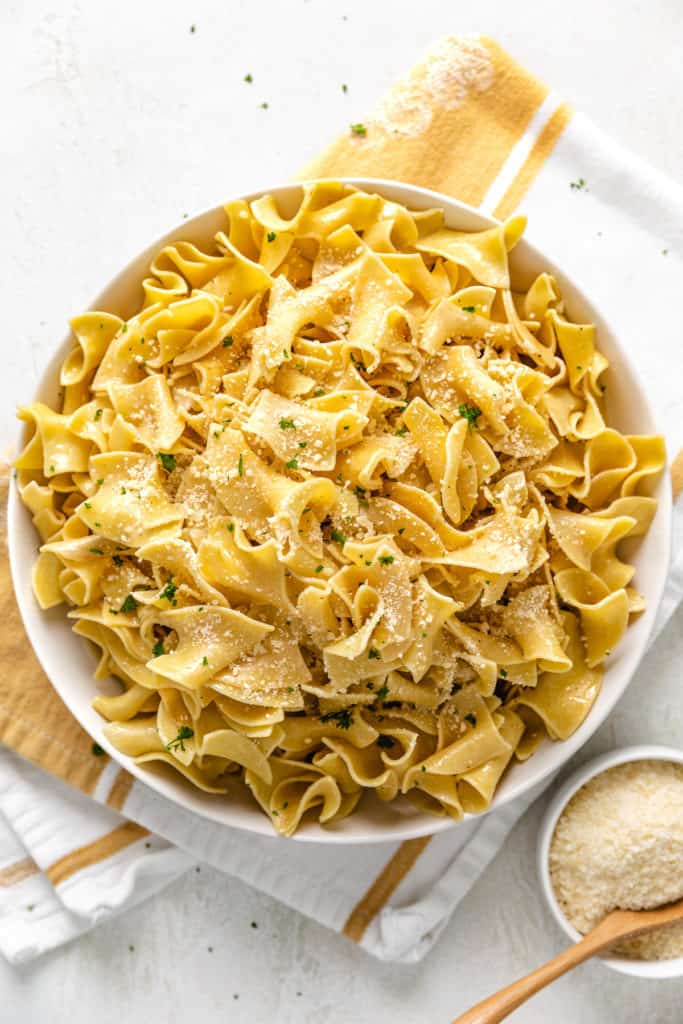 Grated parmesan cheese and parsley sprinkled over egg noodles.