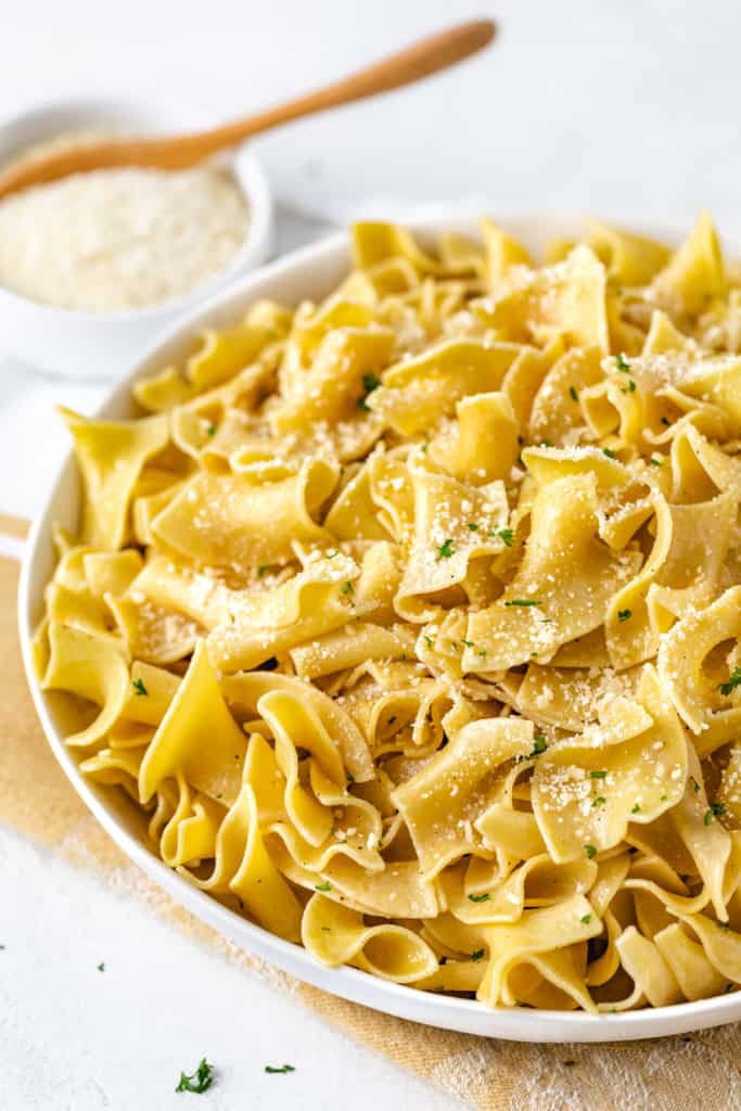 Side view of a large dish of buttered pasta.