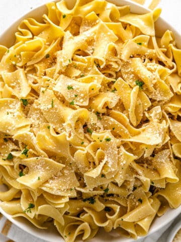 Close up view of parmesan cheese sprinkled over butter noodles.