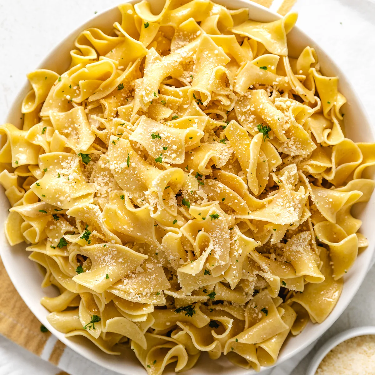 Close up view of parmesan cheese sprinkled over butter noodles.