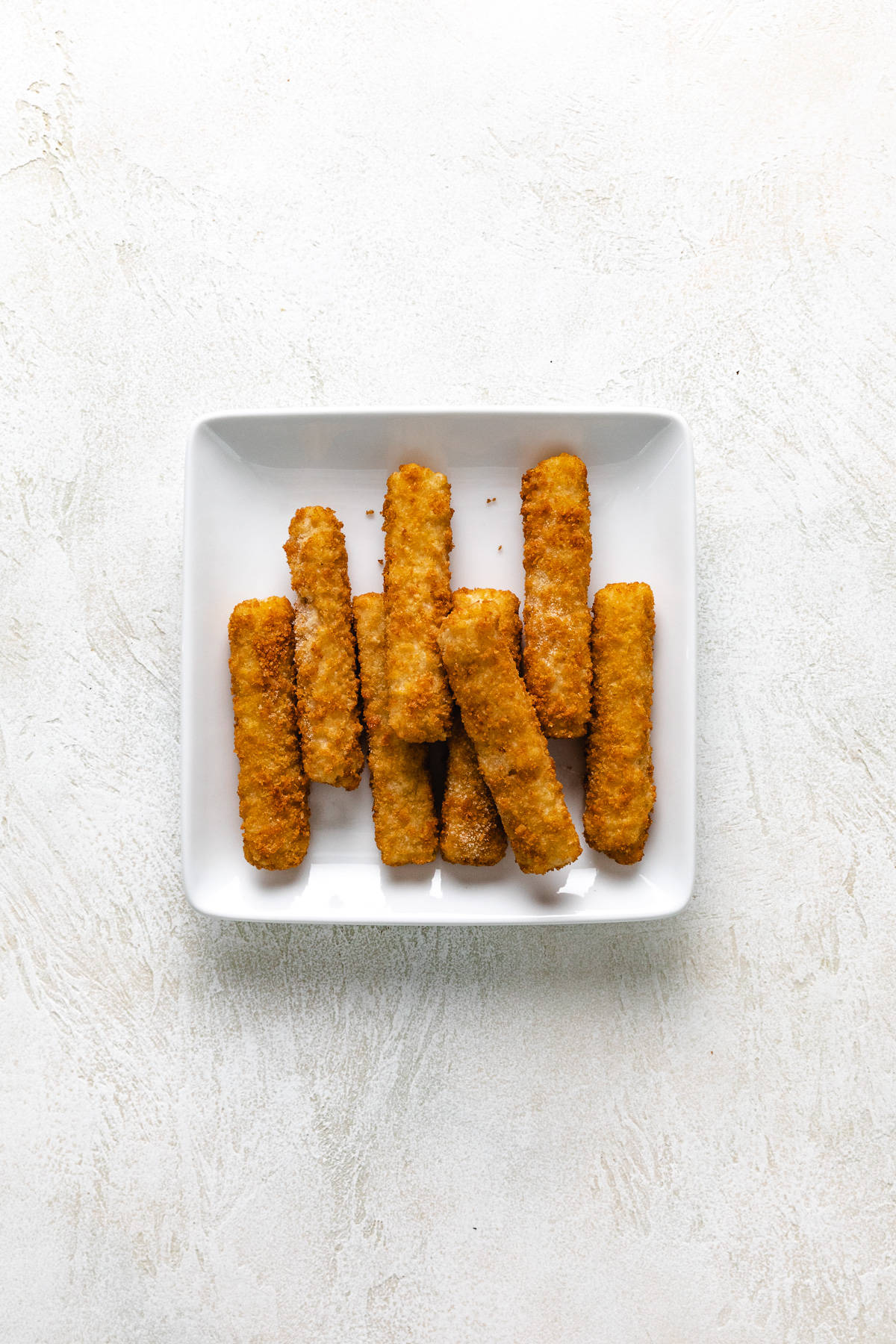 Frozen fish sticks on a white plate.
