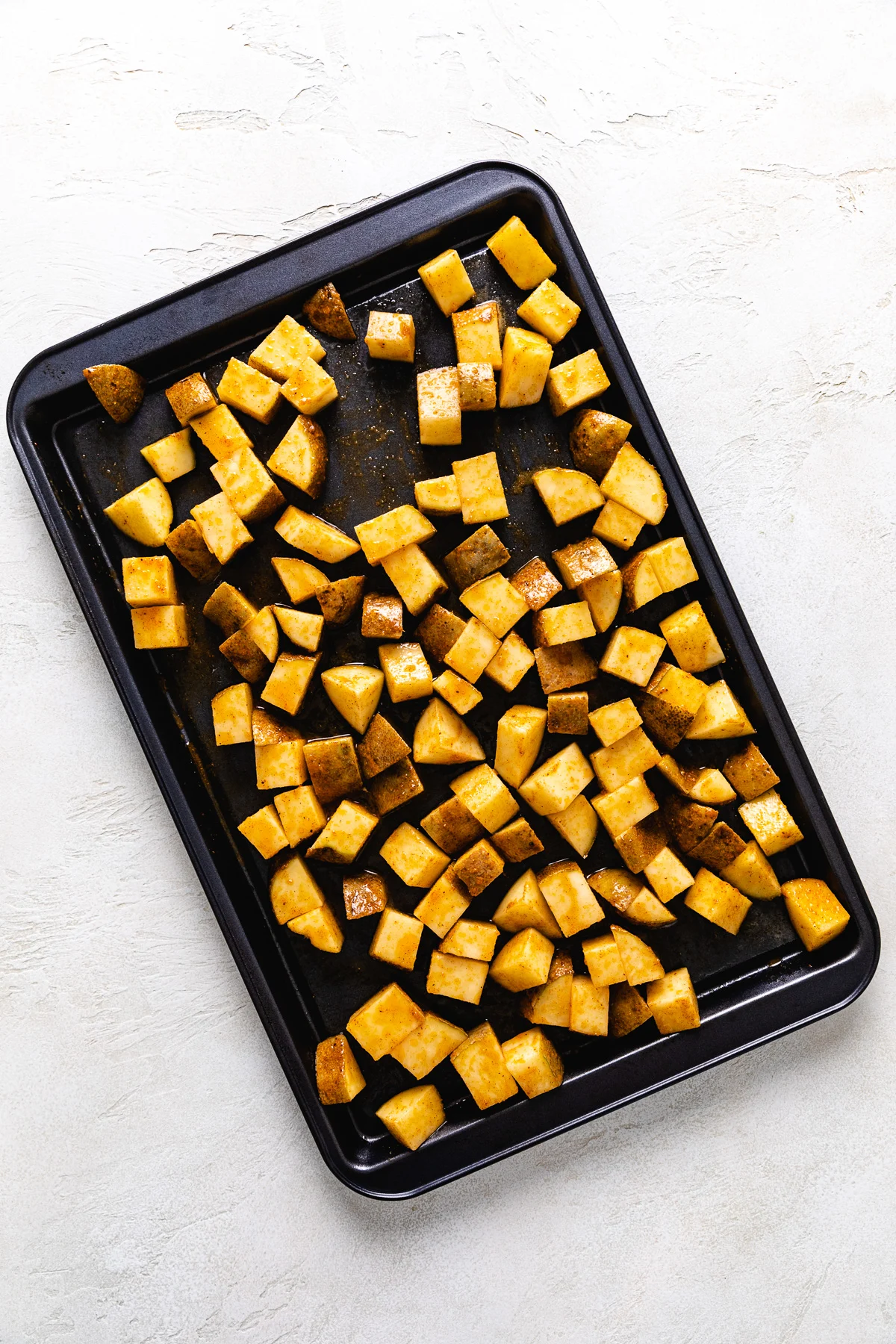 Sheet pan filled with seasoned potatoes.