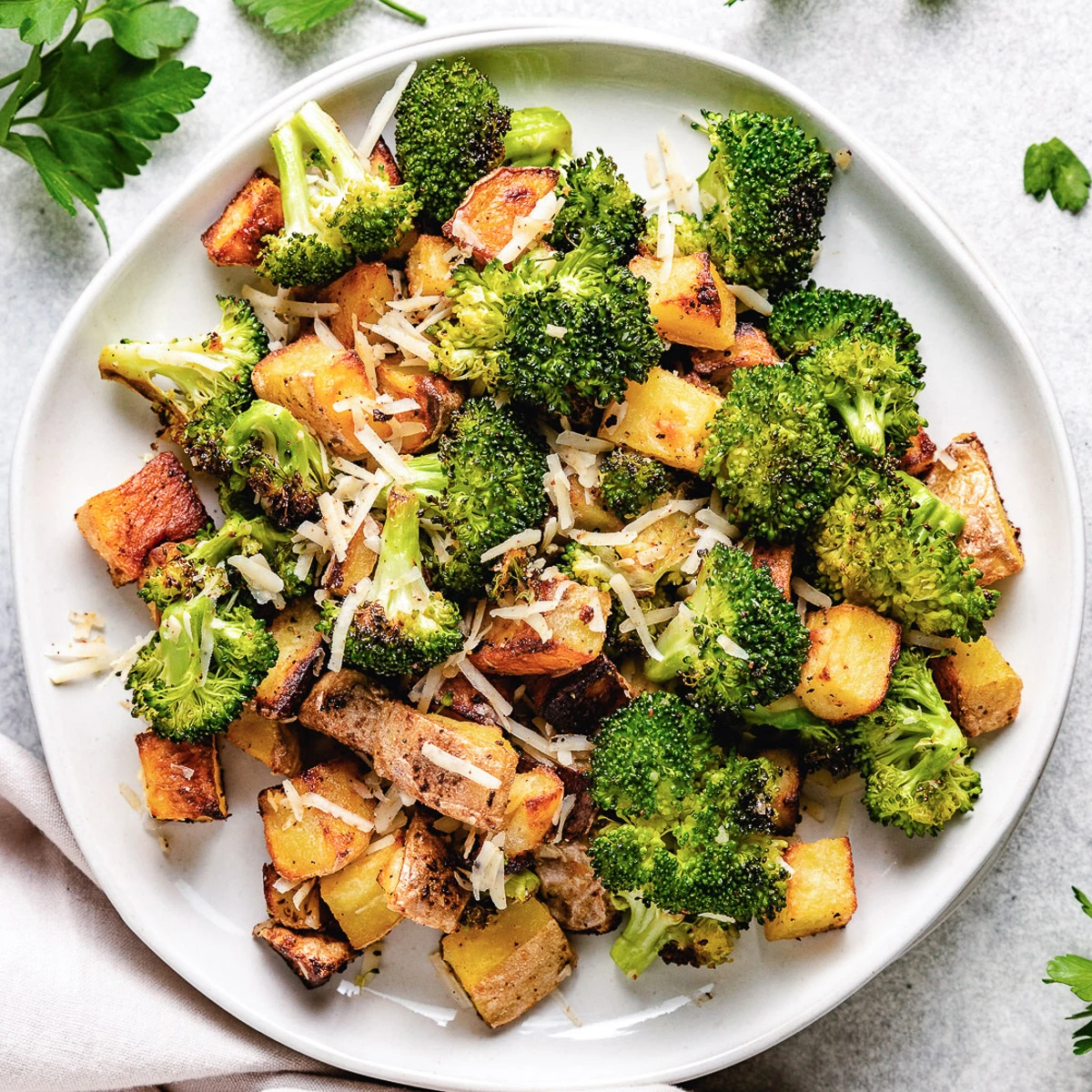 Close up view of roasted potatoes and broccoli with parmesan cheese.