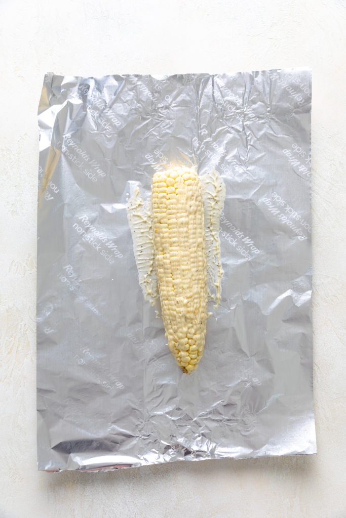Butter ear of corn laying on a piece of foil.