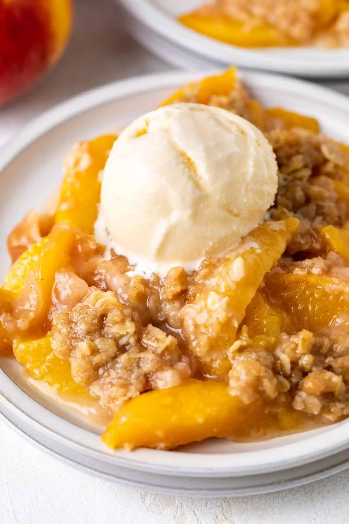 Scoop of ice cream on top of peach crisp.